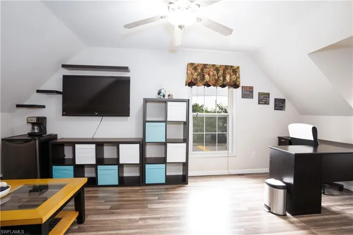 Home office with lofted ceiling, ceiling fan, and hardwood / wood-style floors