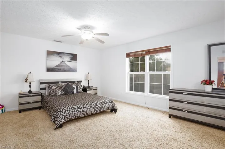 Bedroom featuring light carpet, ceiling fan, and a textured ceiling