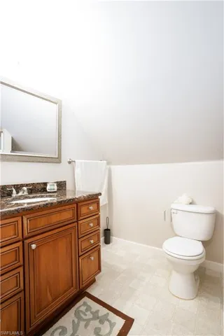 Bathroom featuring vaulted ceiling, vanity, tile patterned floors, and toilet