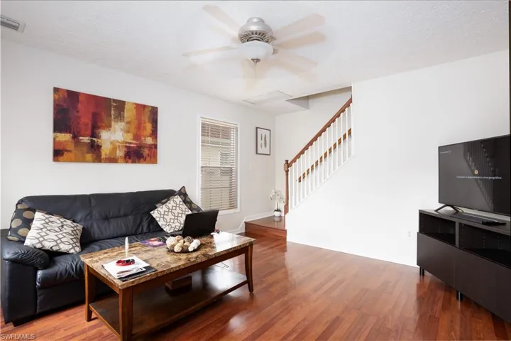 Living room with a textured ceiling, wood-type flooring, and ceiling fan