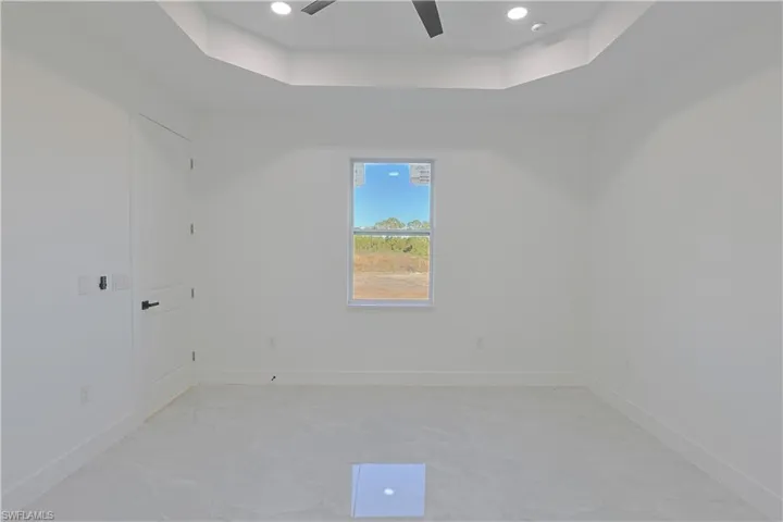 Empty room with a raised ceiling, recessed lighting, baseboards, and ceiling fan