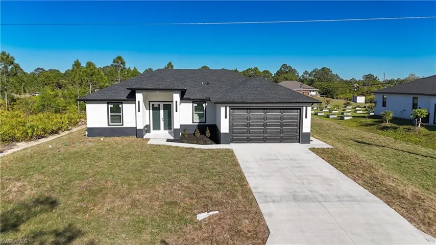 View of front of house featuring a garage, a front lawn, driveway, and french doors