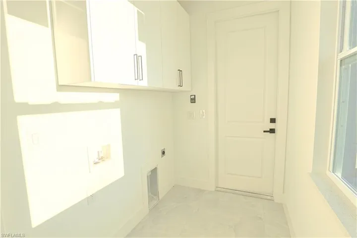 Laundry area with cabinet space, electric dryer hookup, marble finish floor, and baseboards