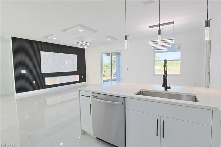 Kitchen with a sink, light countertops, white cabinets, dishwasher, and open floor plan