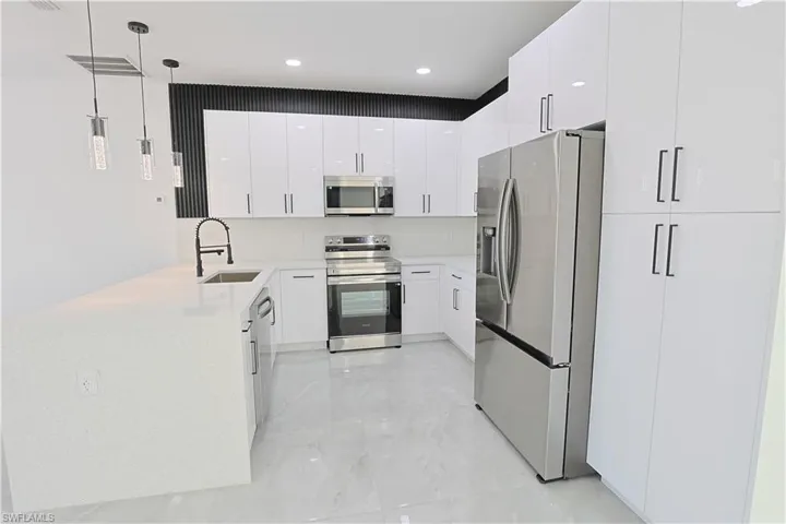 Kitchen with modern cabinets, a sink, white cabinetry, appliances with stainless steel finishes, and a peninsula