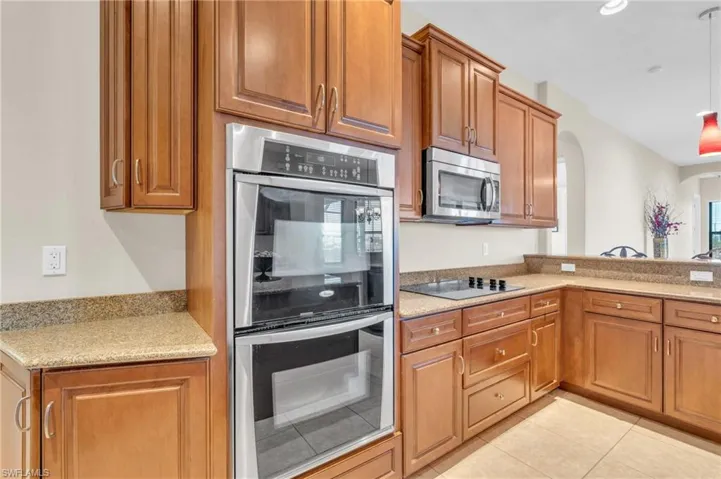 Kitchen with stone countertops, light tile patterned flooring, and appliances with stainless steel finishes