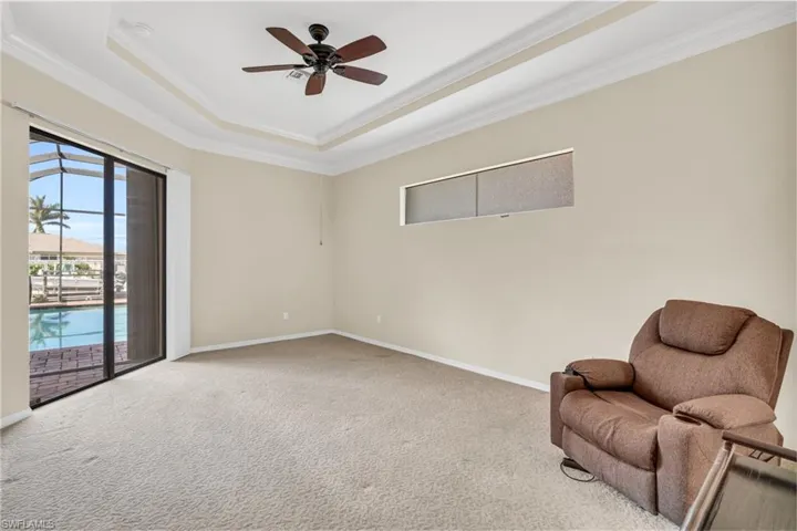 Owners bedroom with carpet floors, a tray ceiling, crown molding, and ceiling fan