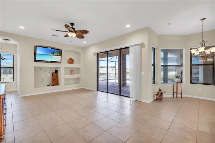 Unfurnished living room featuring light tile patterned floors, built in shelves, and a wealth of natural light