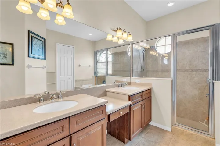 Bathroom with tile floors, a shower with shower door, and vanity