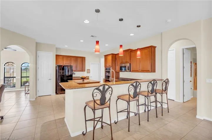 Kitchen with stainless steel appliances,stone countertops, pendant lighting, and an island with sink