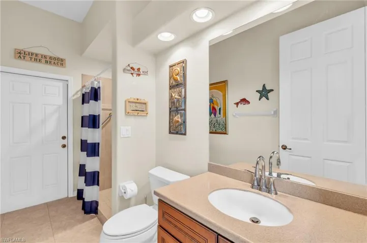 Bathroom featuring tile patterned flooring, toilet, curtained shower, and vanity