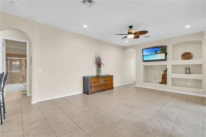 Unfurnished living room featuring built in features, light tile patterned floors, and ceiling fan