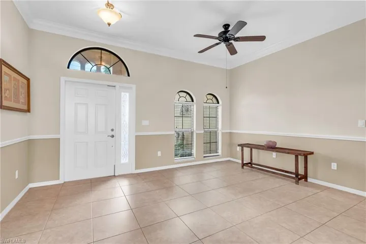 Tiled entryway with crown molding, a wealth of natural light, and ceiling fan