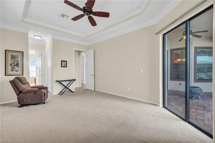 Owners' suite featuring ceiling fan, a raised ceiling, crown molding, and carpet