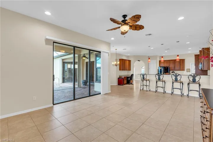 Unfurnished living room featuring light tile patterned flooring and ceiling fan with notable chandelier