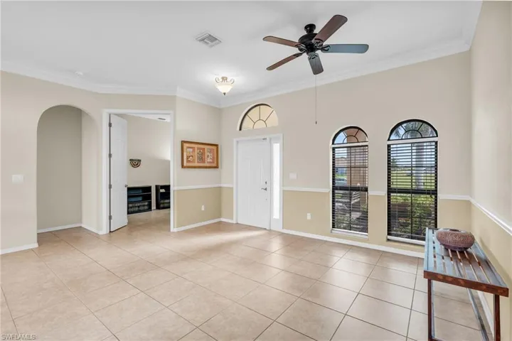 Tiled spare room featuring ceiling fan and crown molding