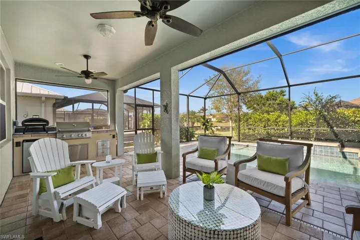 View of patio featuring area for grilling, ceiling fan, glass enclosure, and grilling area