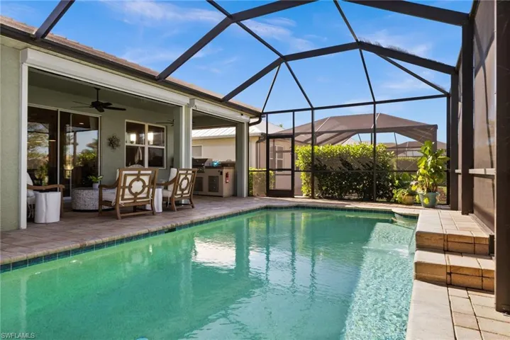 View of swimming pool featuring a lanai, ceiling fan, and a patio area