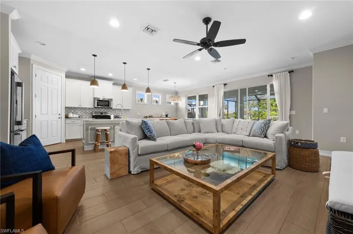 Living room with light hardwood / wood-style floors, ceiling fan, and ornamental molding