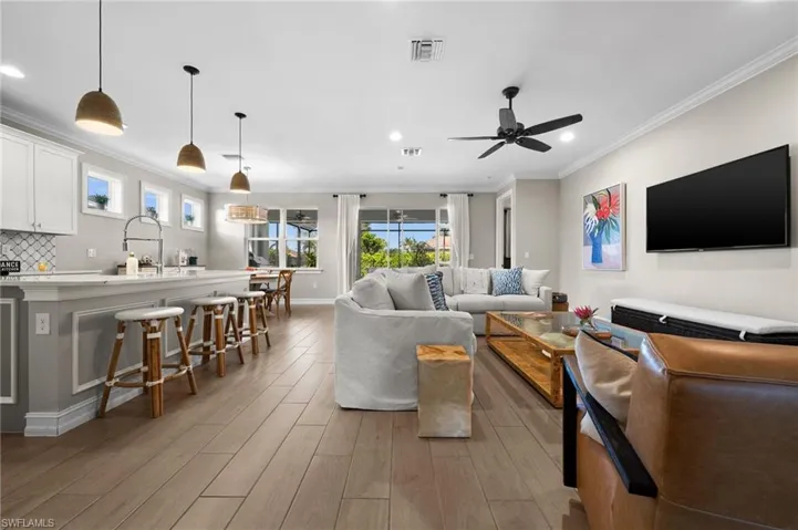 Living room with crown molding, ceiling fan, light hardwood / wood-style flooring, and a healthy amount of sunlight
