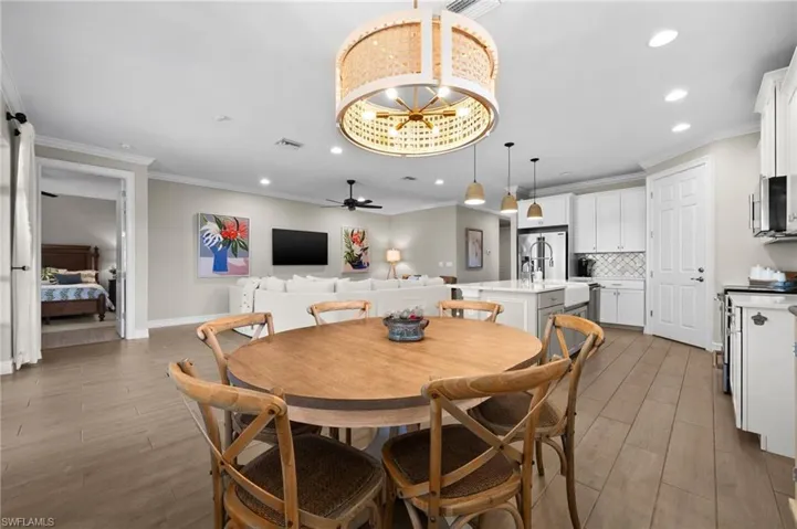Dining area featuring dark hardwood / wood-style floors, ceiling fan with notable chandelier, and ornamental molding