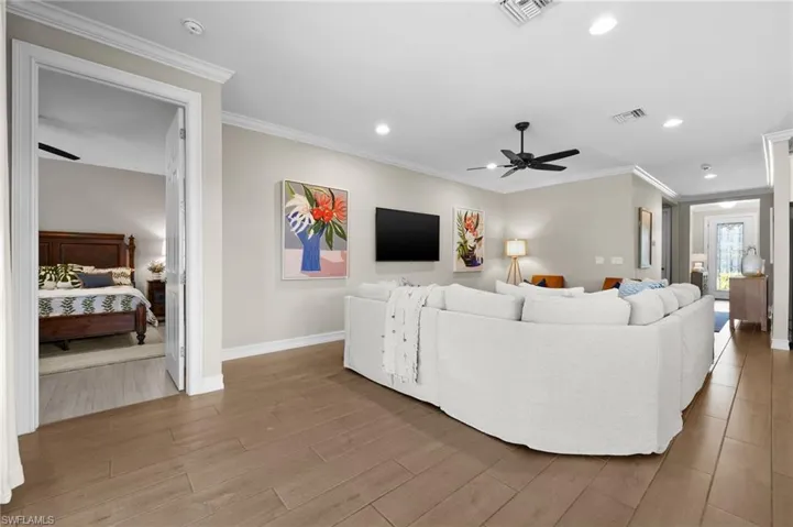Living room with light wood-type flooring, ceiling fan, and crown molding