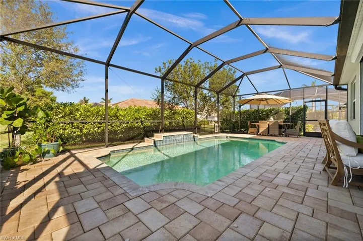 View of swimming pool with glass enclosure, a patio, and a hot tub