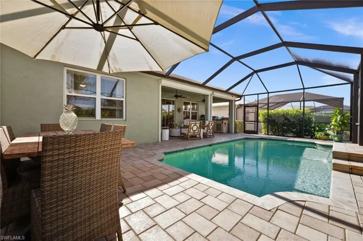 View of pool featuring a lanai, ceiling fan, pool water feature, and a patio
