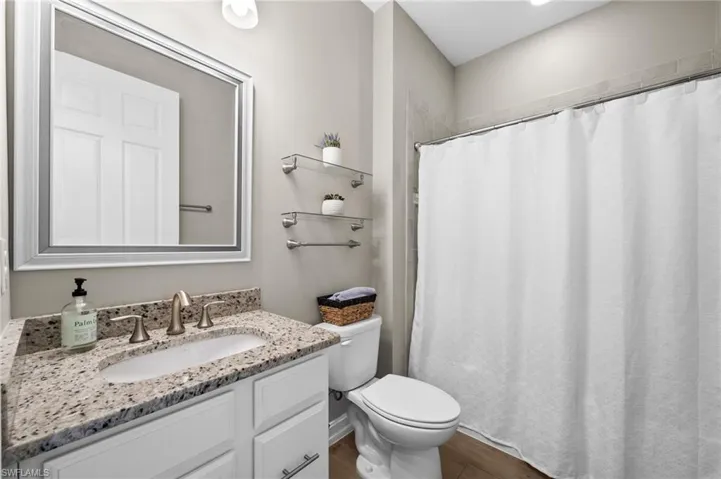 Bathroom with hardwood / wood-style flooring, vanity, and toilet