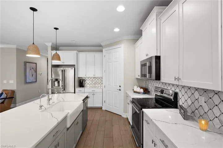 Kitchen with white cabinetry, hanging light fixtures, and appliances with stainless steel finishes