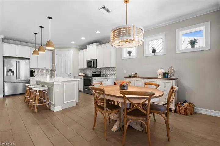 Dining space with ornamental molding, sink, a wealth of natural light, and light hardwood / wood-style flooring