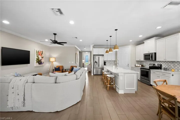 Living room with light hardwood / wood-style floors, ceiling fan, crown molding, and sink