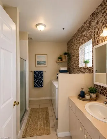 Bathroom featuring a vanity with an integrated sink, a glass-enclosed shower, and tile flooring