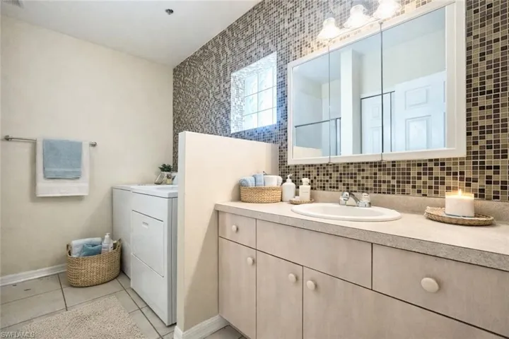 Bathroom vanity with an integrated sink, tri-fold mirrored medicine cabinet, and three-light fixture