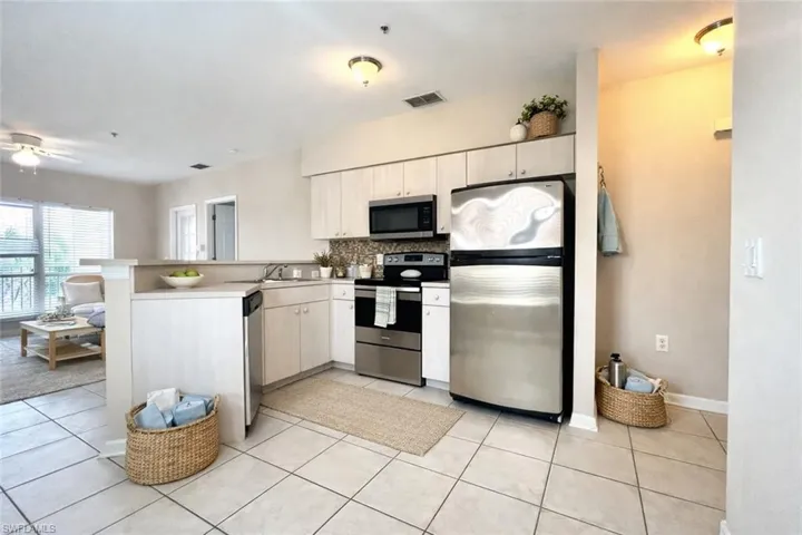 Kitchen featuring stainless steel appliances, light-toned cabinetry, and a mosaic tile backsplash