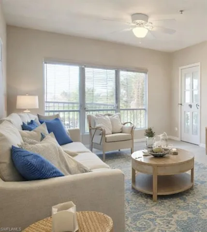 Living area featuring large windows with horizontal blinds, a white ceiling fan with integrated lighting, a glass-paned door, and light-toned wall paint