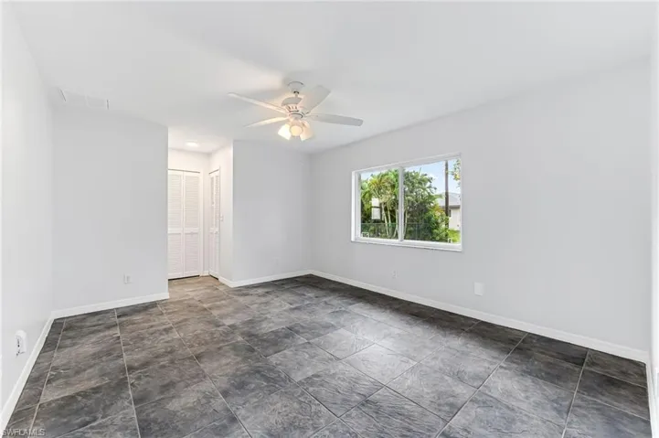 Empty room with ceiling fan and dark tile patterned floors