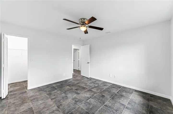 Empty room featuring ceiling fan and dark tile patterned floors