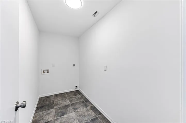 Laundry room with dark tile patterned flooring, hookup for a washing machine, and electric dryer hookup