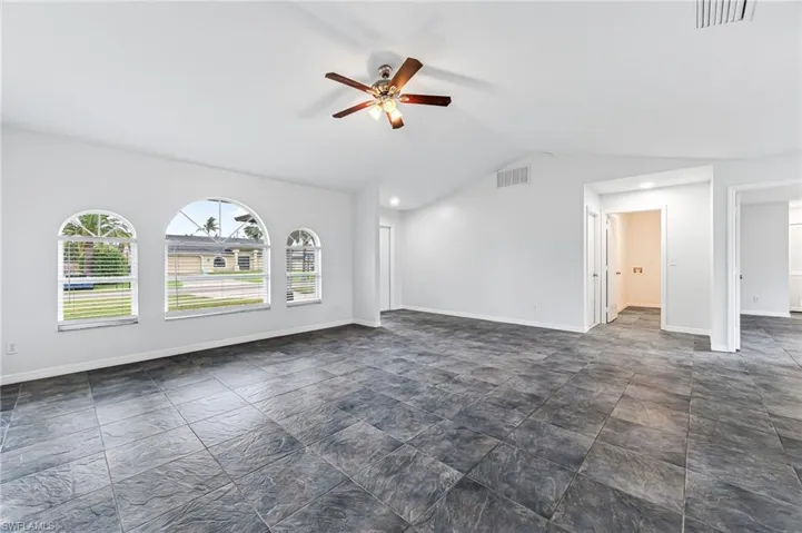 Tiled spare room featuring ceiling fan and lofted ceiling