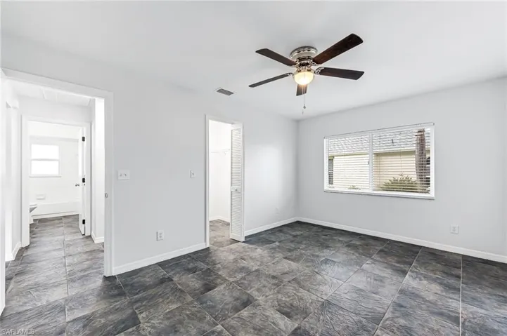 Spare room featuring dark tile patterned flooring, ceiling fan, and plenty of natural light