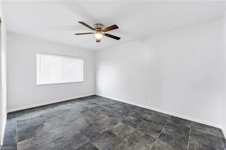 Tiled empty room featuring ceiling fan