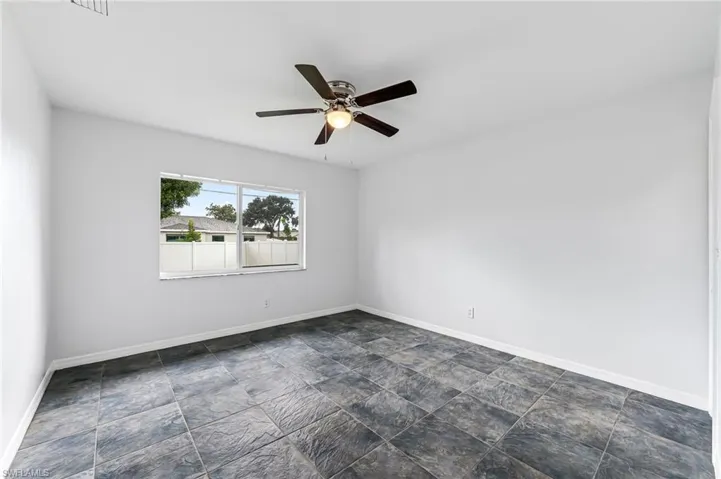 Spare room with ceiling fan and dark tile patterned floors