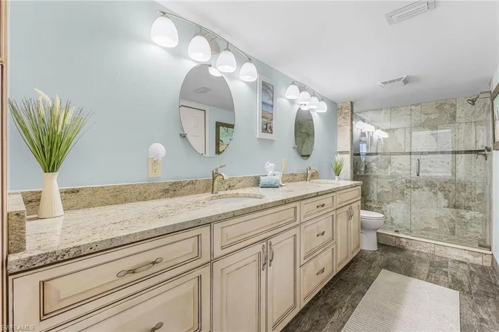 The primary bathroom has a raised vanity with a granite countertop with dual sinks, a spacious shower, a walk-in closet and a linen closet.