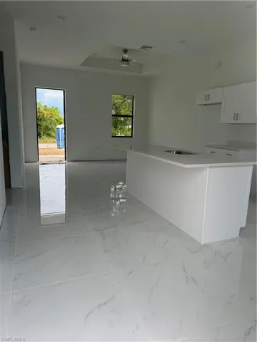 Kitchen featuring white cabinetry, light tile flooring, plenty of natural light, and ceiling fan