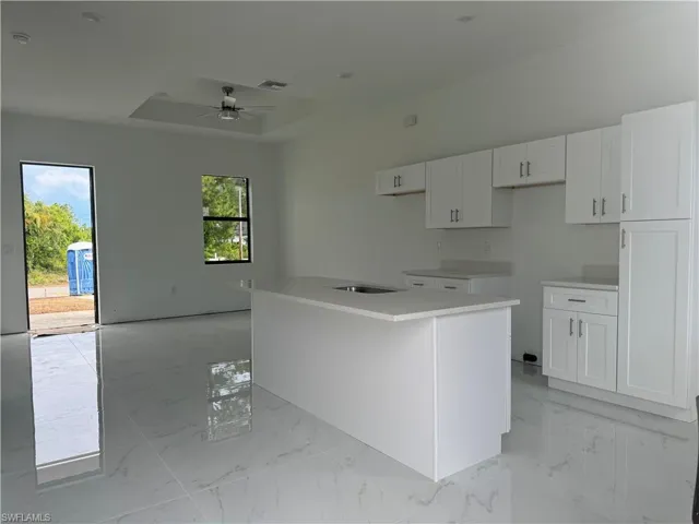 Kitchen featuring a center island, a healthy amount of sunlight, ceiling fan, and a raised ceiling