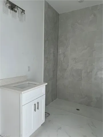 Bathroom with a tile shower, tile flooring, and sink