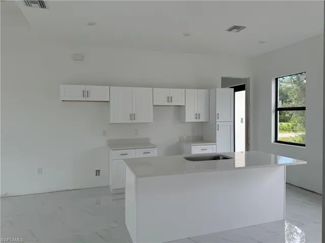 Kitchen featuring white cabinets, a kitchen island, and light tile floors