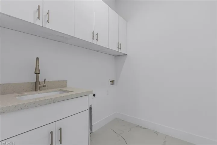 Laundry room with electric dryer hookup, washer hookup, light marble finish flooring, and cabinet space