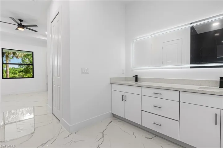 Bathroom with marble look tiles, double vanity, and ceiling fan